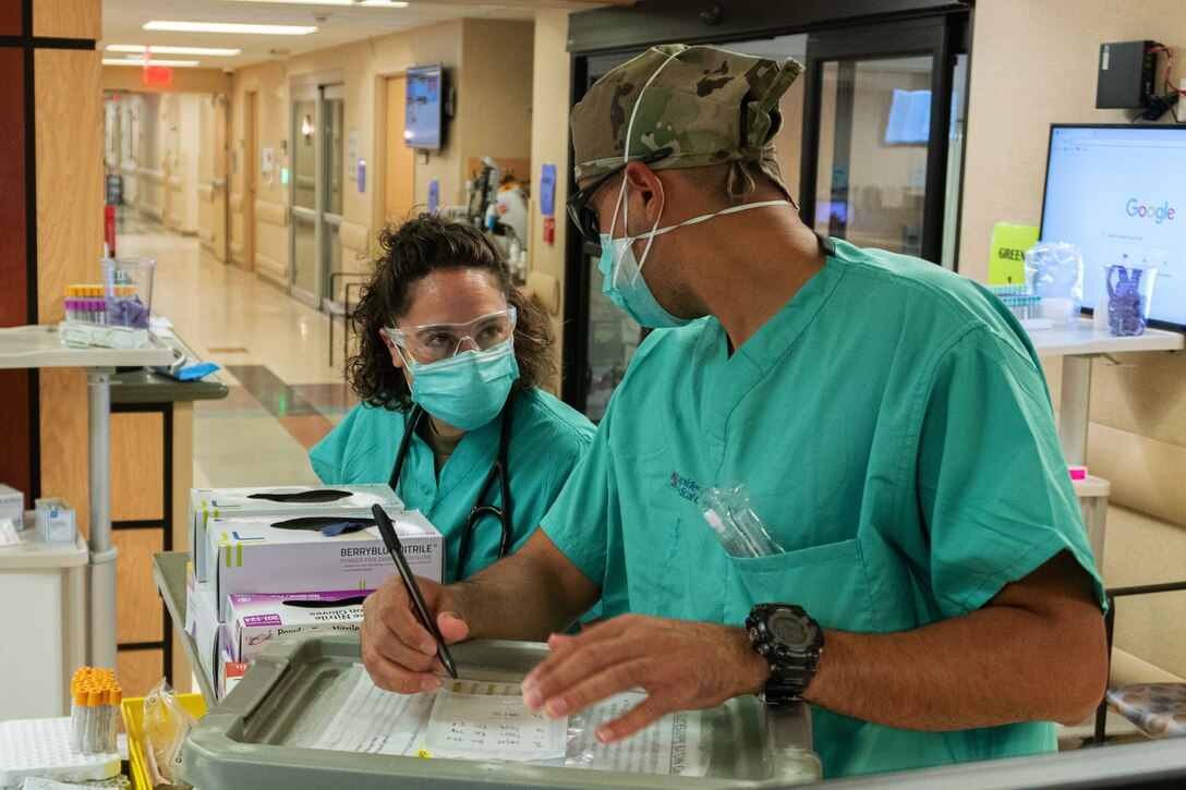 Two airmen wearing face masks have a discussion.