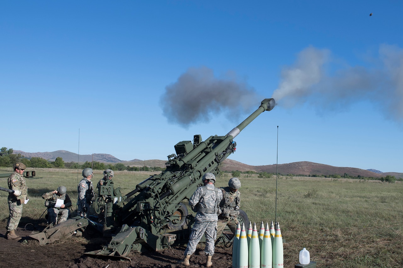 Soldiers fire a large gun.