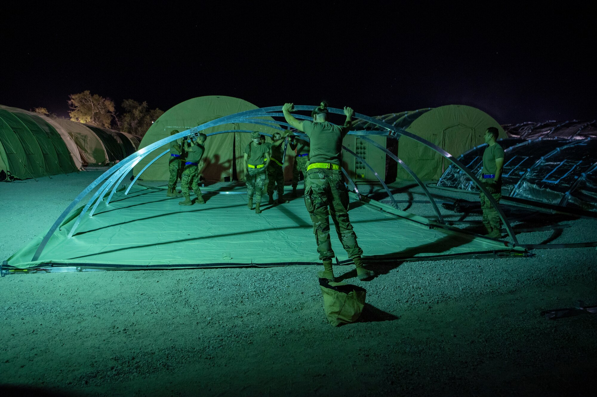 Airmen with the 635th Material Maintenance Squadron, 49th Civil Engineer Squadron, and the 49th Wing set up the foundation of a housing tent as part of Task Force-Holloman, Aug. 27, 2021, on Holloman Air Force Base, New Mexico. The Department of Defense, through U.S. Northern Command, and in support of the Department of Homeland Security, is providing transportation, temporary housing, medical screening, and general support for up to 50,000 Afghan evacuees at suitable facilities, in permanent or temporary structures, as quickly as possible. This initiative provides Afghan personnel essential support at secure locations outside Afghanistan. (U.S. Air Force Photo by Airman 1st Class Jessica Sanchez-Chen)