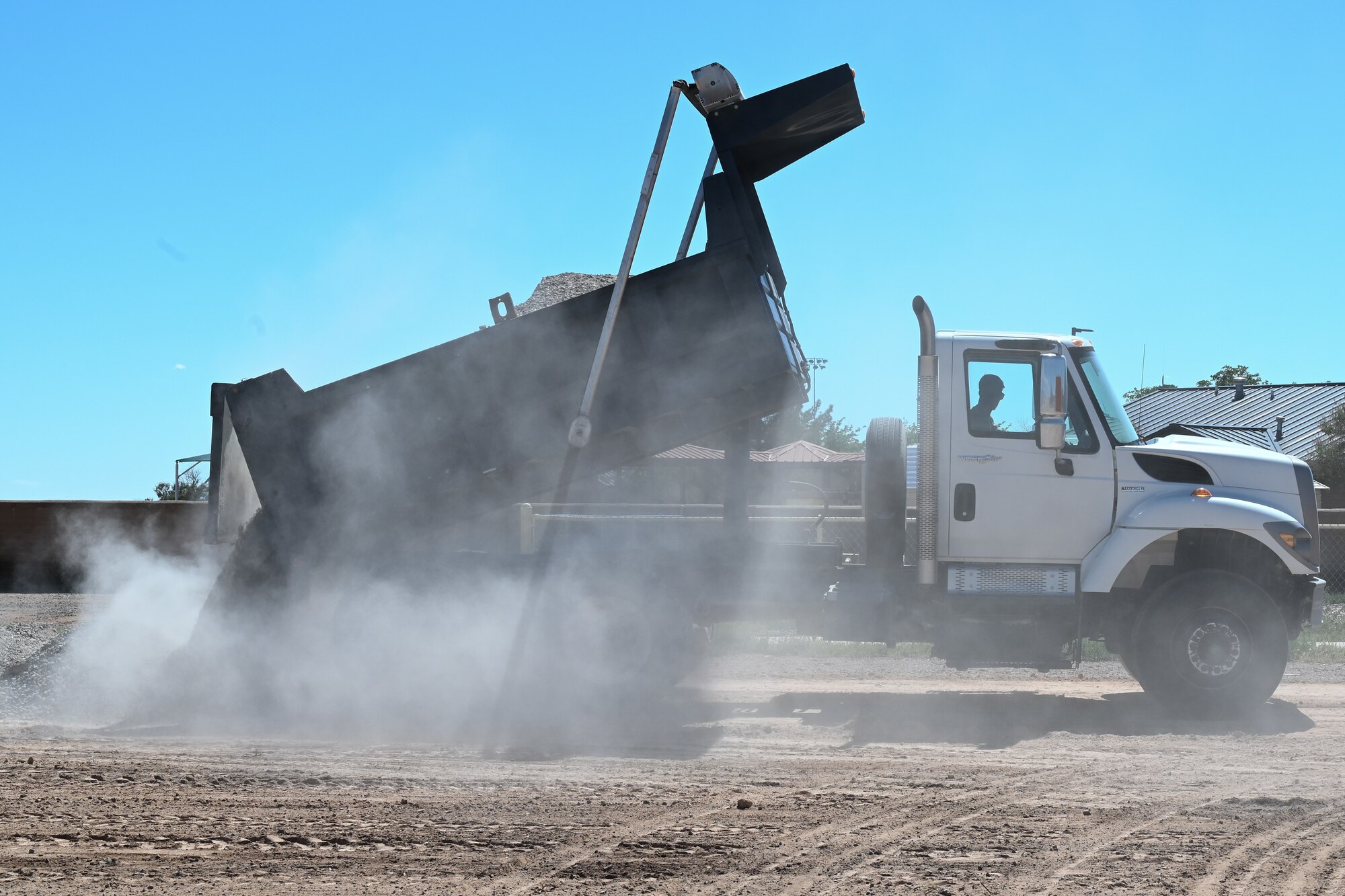 A 49th Civil Engineer Squadron airman drops gravel at a future housing site for Task Force-Holloman personnel Aug. 26, 2021 on Holloman Air Force Base, New Mexico. The Department of Defense, through U.S. Northern Command, and in support of the Department of Homeland Security, is providing transportation, temporary housing, medical screening, and general support for up to 50,000 Afghan evacuees at suitable facilities, in permanent or temporary structures, as quickly as possible. This initiative provides Afghan personnel essential support at secure locations outside Afghanistan. (U.S. Air Force photo by Tech. Sgt. BreeAnn Sachs)