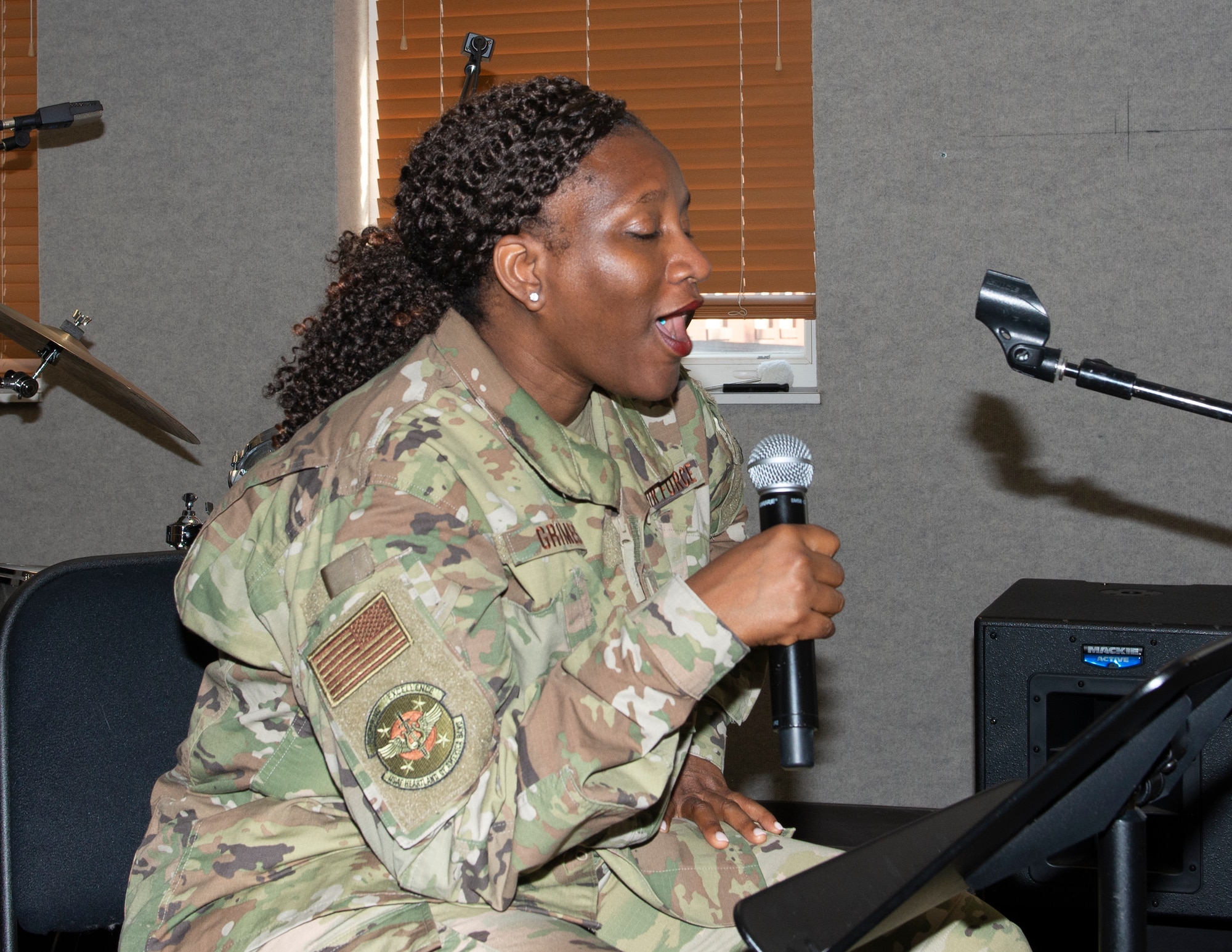 female airman sitting holding a microphone in her hand singing