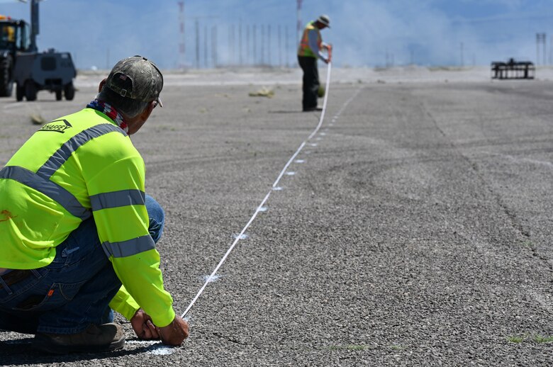 Two contractors prepare guide lines at a future Afghan personnel housing facility construction site in support of Operation Allies Welcome, Aug. 27, 2021, on Holloman Air Force Base, New Mexico. The Department of Defense, through U.S. Northern Command, and in support of the Department of Homeland Security, is providing transportation, temporary housing, medical screening, and general support for up to 50,000 Afghan evacuees at suitable facilities, in permanent or temporary structures, as quickly as possible. This initiative provides Afghan personnel essential support at secure locations outside Afghanistan. (U.S. Air Force photo by Staff Sgt. Christopher S. Sparks)