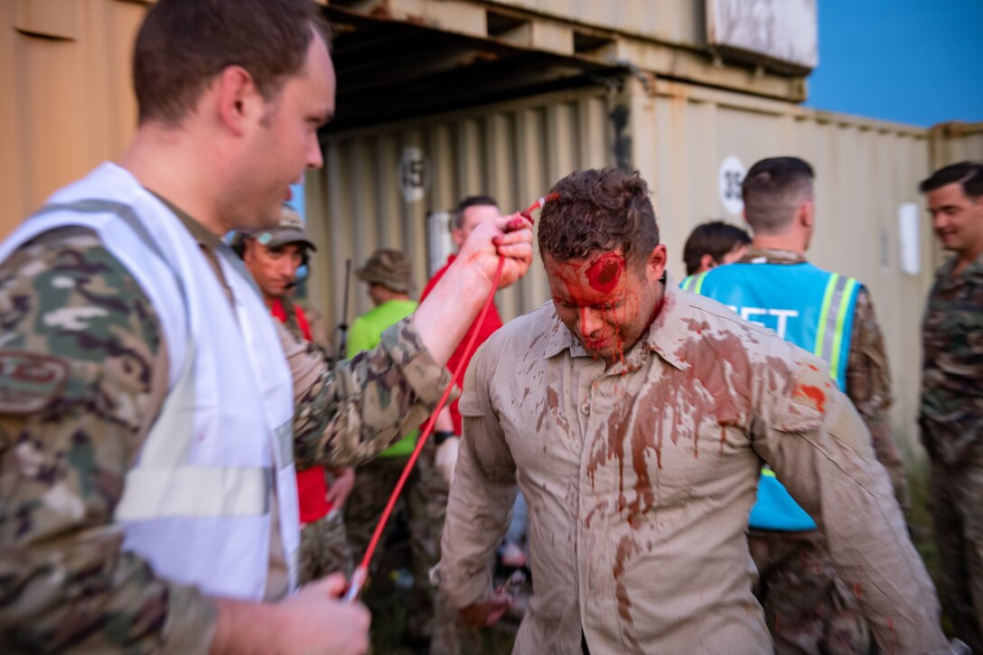 Photo of Airman applying moulage to another Airman