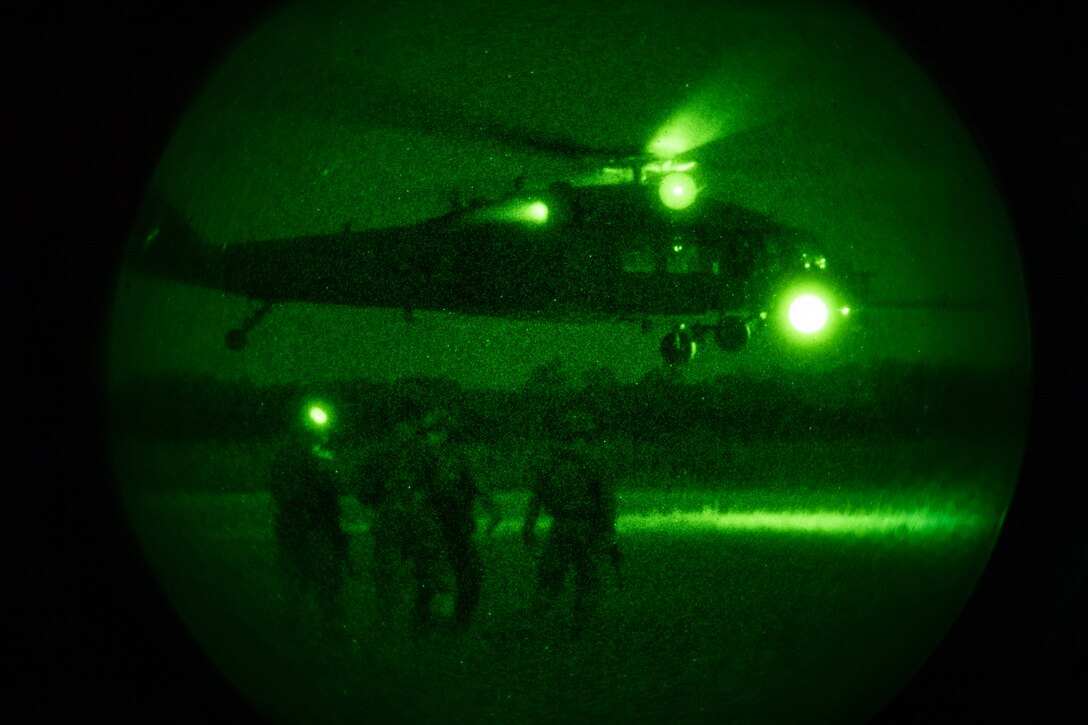 Photo of Airmen in front of a helicopter