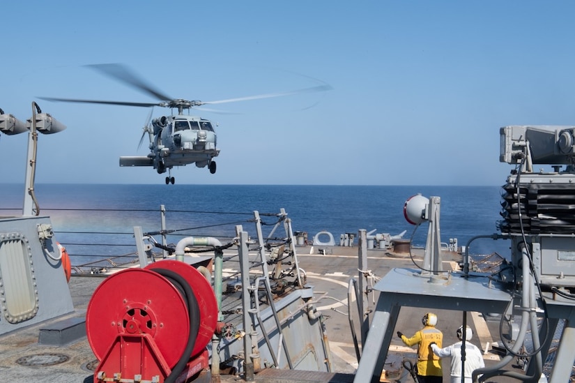 A helicopter prepares to land on a ship.