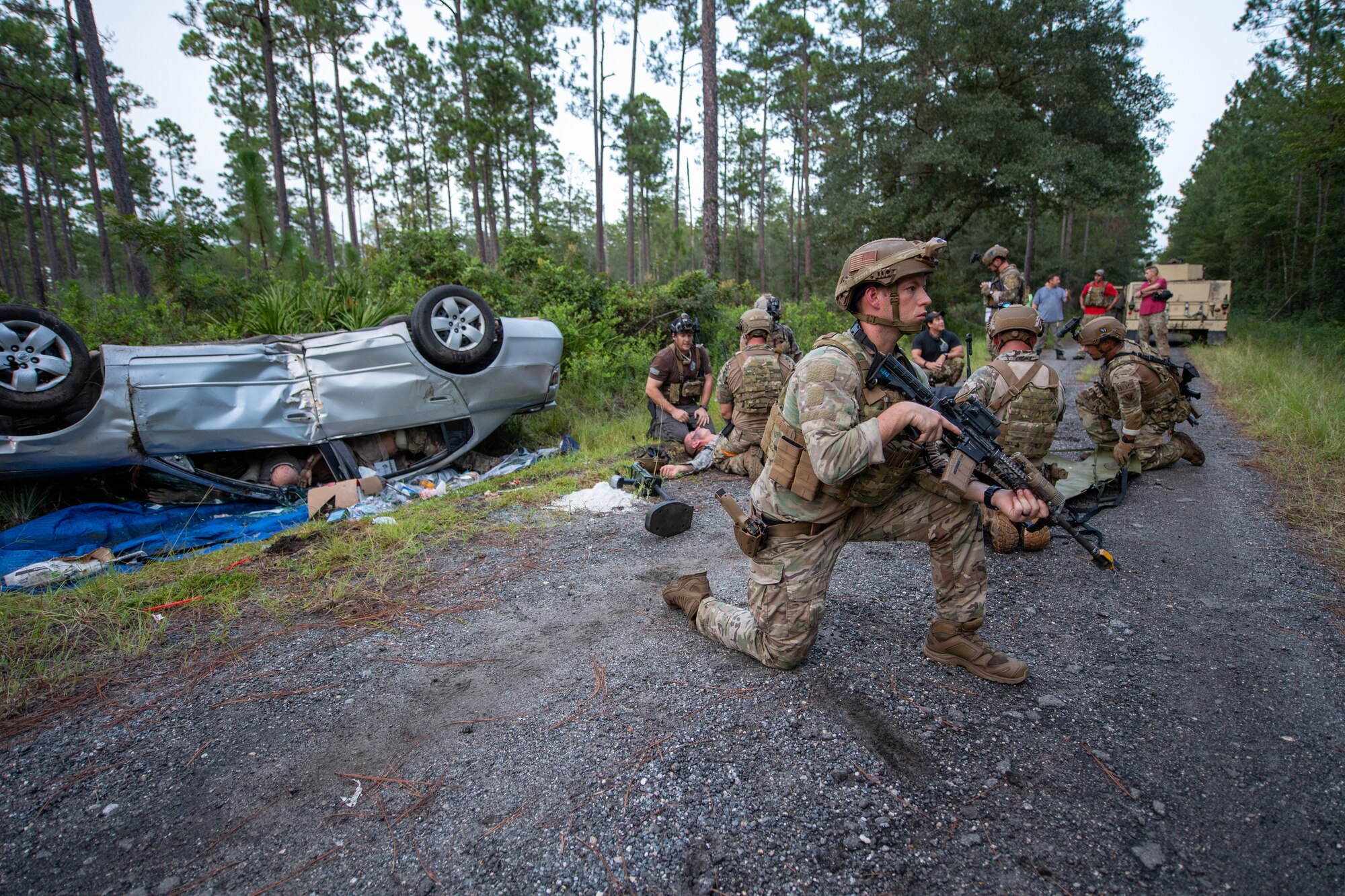 Photo of Airmen kneeling next to a flipped car