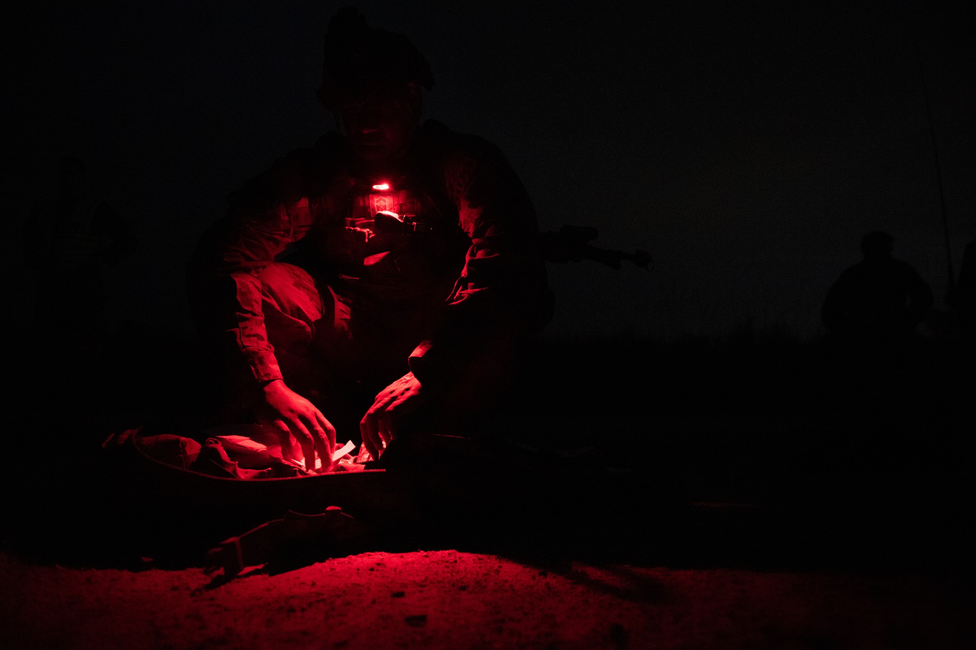 Photo of Airmen looking into a bag at night