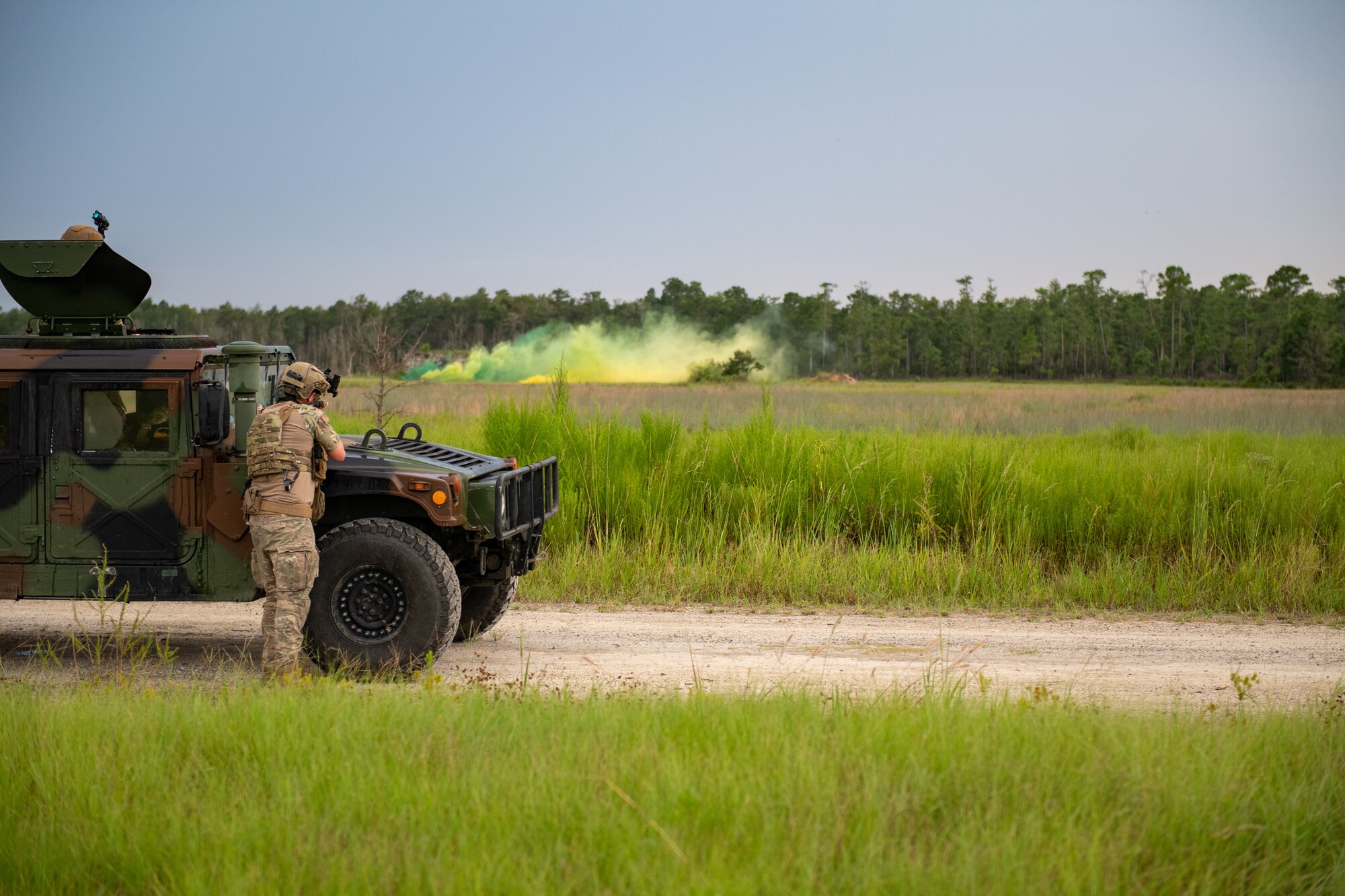 Photo of Airman with a rifle in front of a Humvee