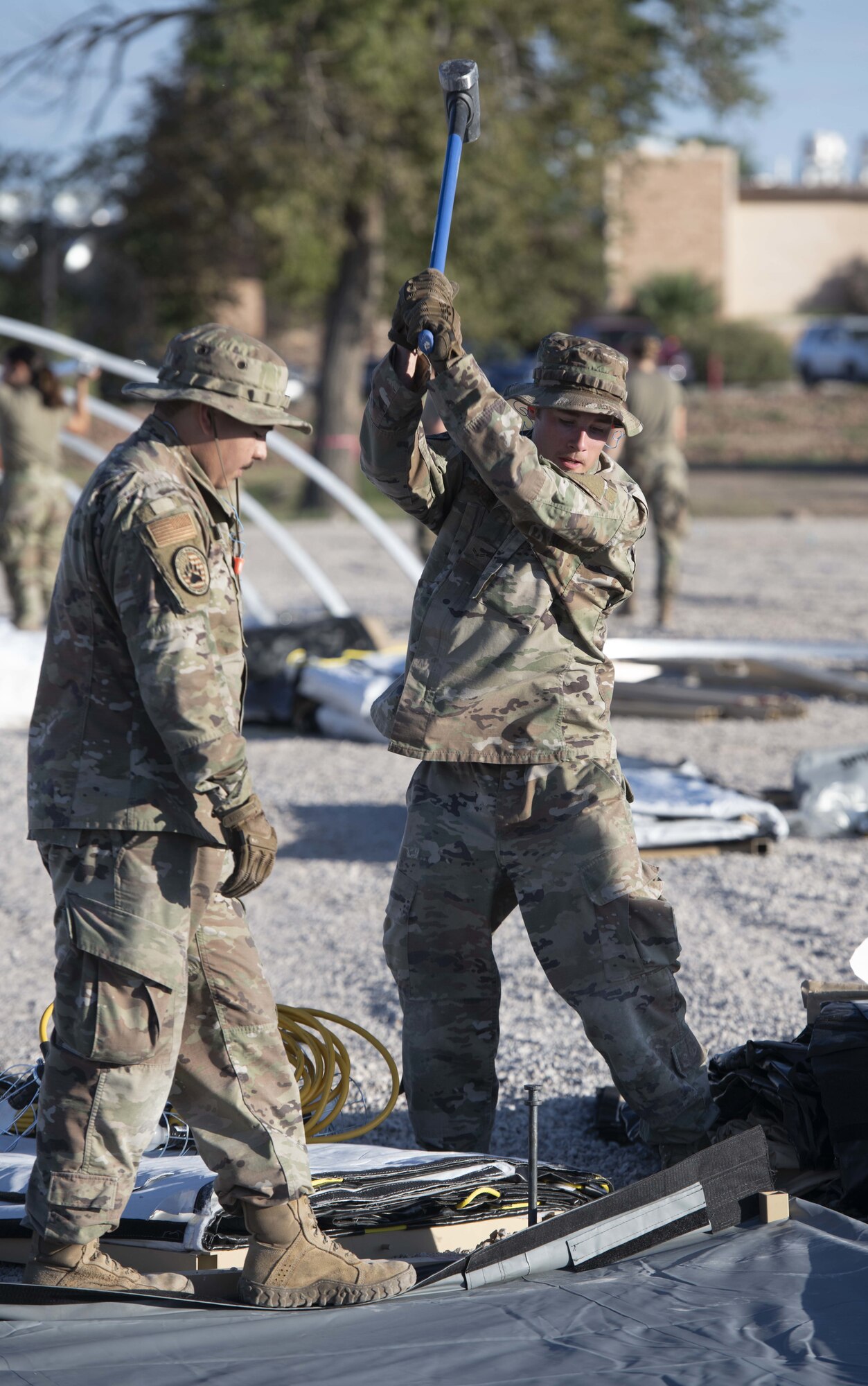 Airman 1st Class Rudy Villasenor, left, and Airman 1st Class Jeremy Price, 635th Materiel Maintenance Squadron journeymen, hammer in spikes to hold down the floor structure of a housing tent in support of Operation Allies Welcome, August 27, 2021, on Holloman Air Force Base, New Mexico.. The Department of Defense, through U.S. Northern Command, and in support of the Department of Homeland Security, is providing transportation, temporary housing, medical screening, and general support for up to 50,000 Afghan evacuees at suitable facilities, in permanent or temporary structures, as quickly as possible. This initiative provides Afghan personnel essential support at secure locations outside Afghanistan. (U.S. Air Force photo by Staff Sgt. Timothy Young)