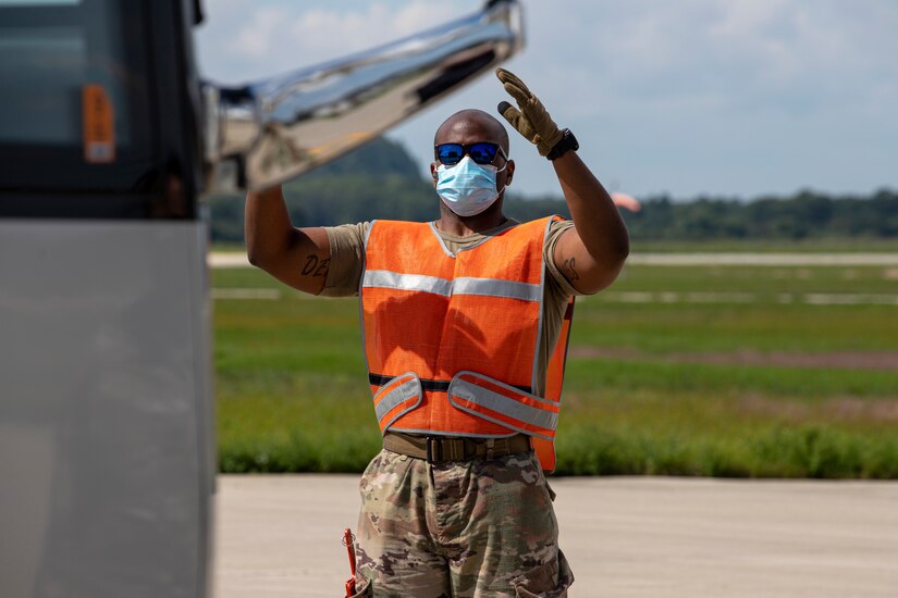 An Airman from the Kentucky Air National Guard's 123rd Contingency Response Group guides a bus into place to receive Afghan evacuees departing a plane at Volk Field, Wis., Aug. 29, 2021. The Department of Defense, in support of the Department of Homeland Security and the Department of State, is providing transportation and temporary housing for evacuees as part of Operation Allies Refuge. The initiative follows through on America’s commitment to Afghan personnel who have helped the United States, and provides them essential support at secure locations outside Afghanistan. (U.S. Army photo by Spc. Rhianna Ballenger, 55th Signal Company)