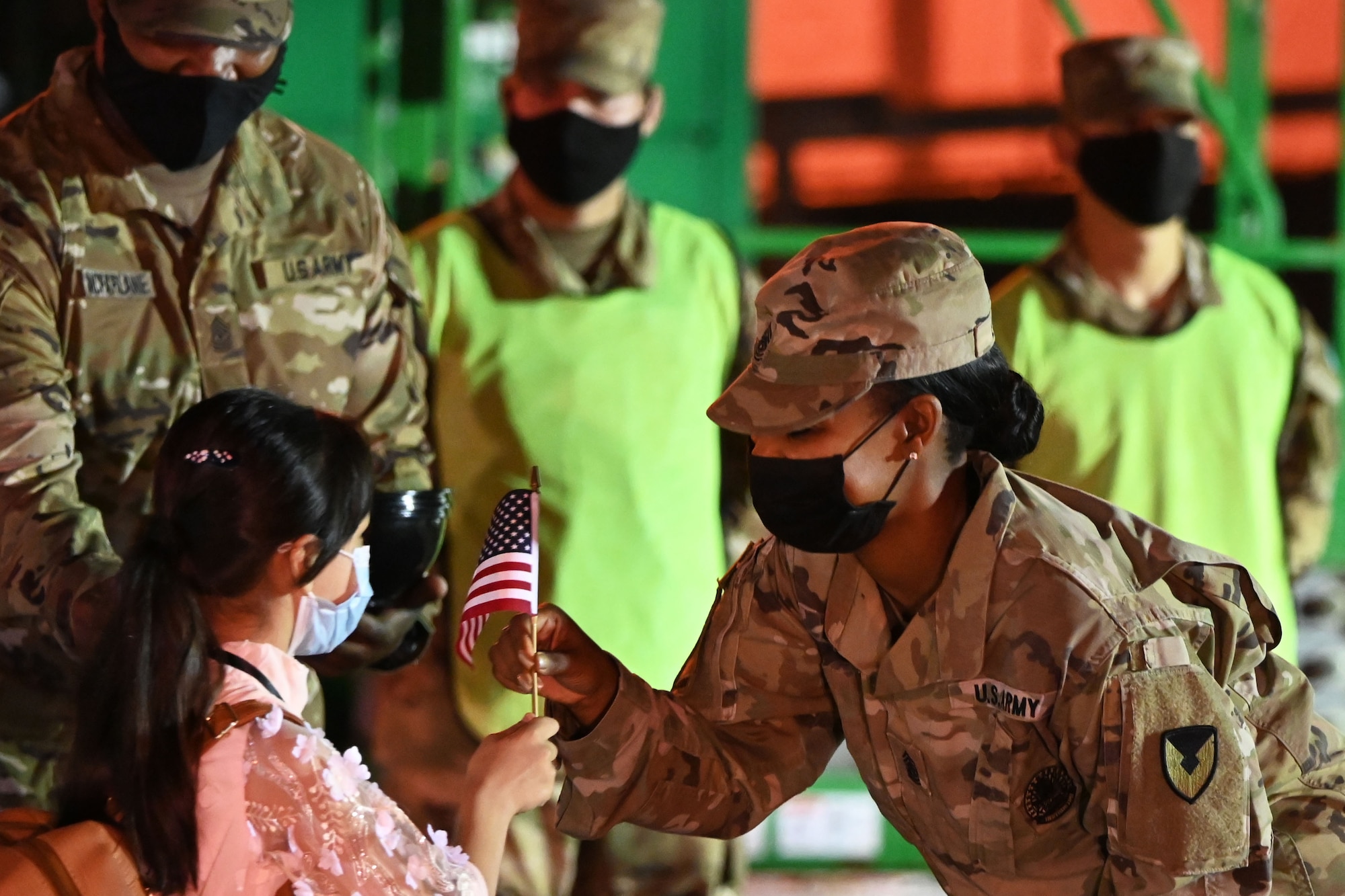 A soldier hands a U.S. flag to a child.