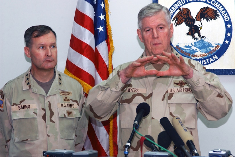 Two men in old pattern camouflage uniforms speak.