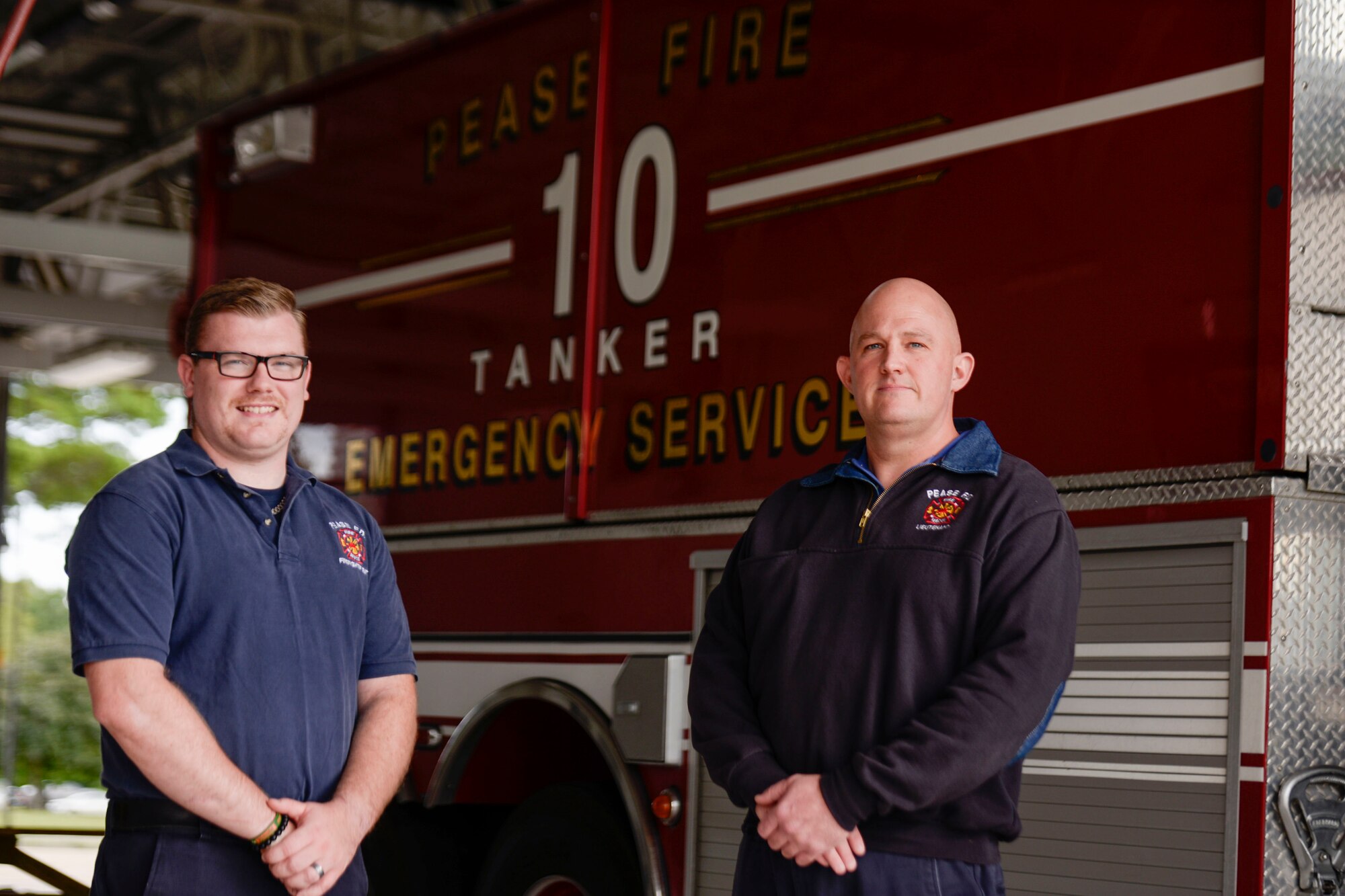 Thomas Gleason Jr. and Derek Murdock, firefighters with Pease Fire & Emergency Services pose for a portrait in front of a firetruck at Pease Air National Guard Base.