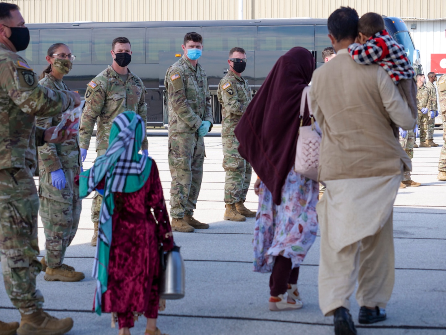 Afghan evacuees arrive in Indianapolis Sept. 2, 2021, as 1st Cavalry Division Soldiers watch. Hoosiers will host the Afghans at Camp Atterbury, near Edinburgh, as they begin their safe resettlement to the United States. The division Soldiers along with Indiana National Guard Soldiers will provide transportation, temporary housing, medical screening and logistics support as part of Operation Allies Welcome.
