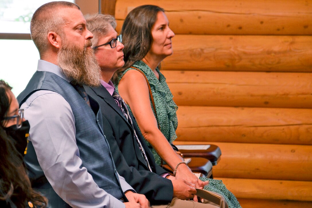 Two women and a man attend a service.