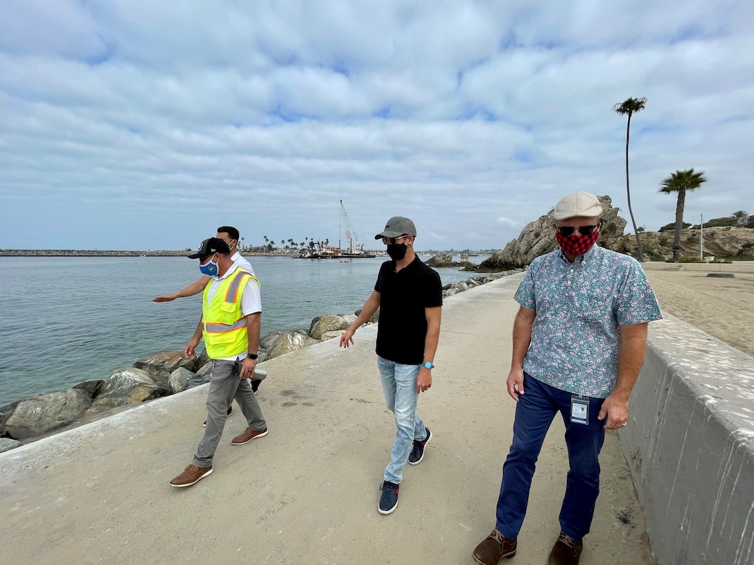 Mark Golay, second from right, U.S. Army Corps of Engineers Los Angeles District Navigation Branch program manager, accompanies Chris Miller, right, public works manager with the City of Newport Beach; Robert Silva, left-foreground, construction inspection supervisor with the City of Newport Beach; and Jorge Tomas, director of operations and sales with Pacific Dredge, on a walkthrough of the Newport Bay Harbor east jetty Sept. 1, 2021, in Newport Beach, California.