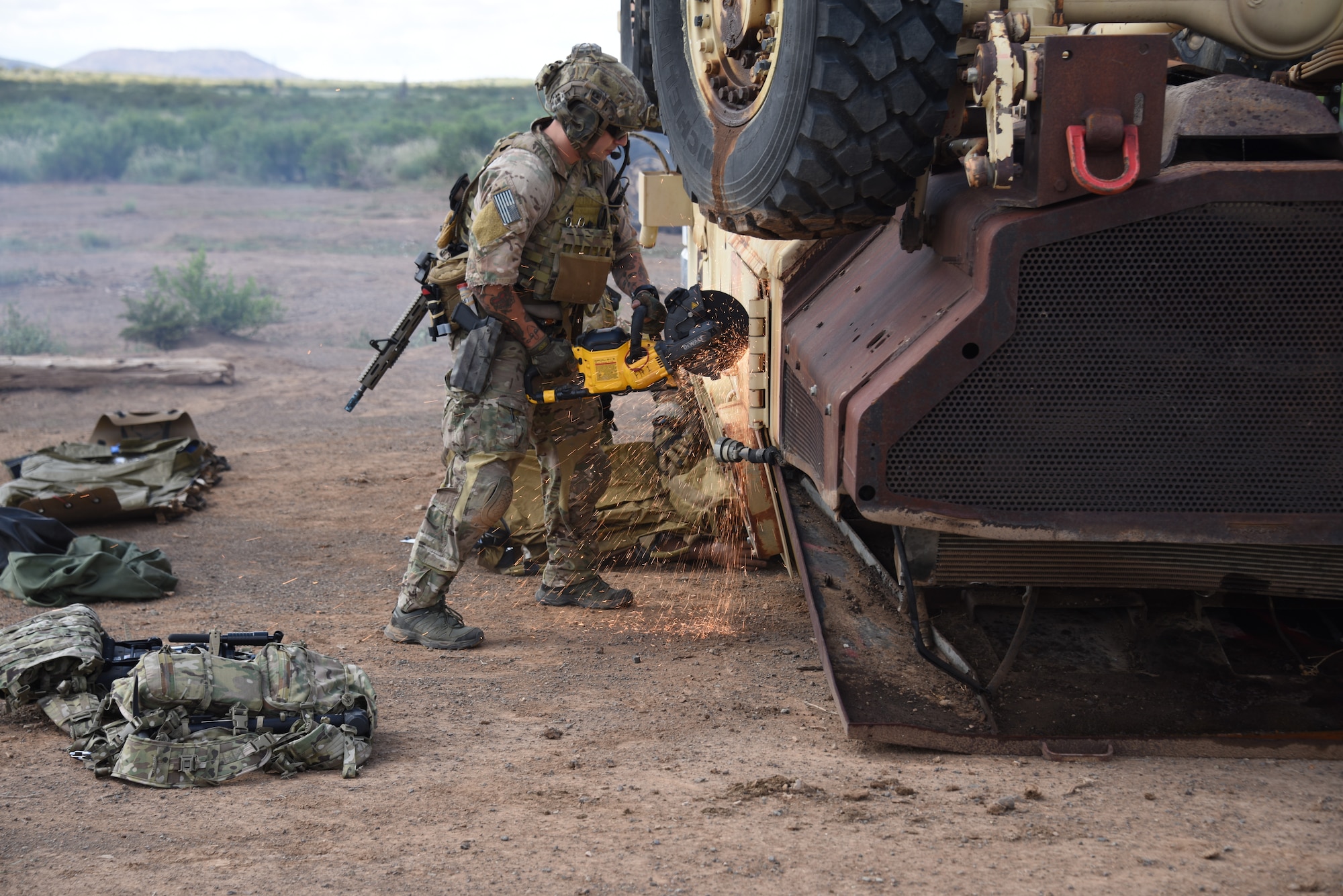 A photo of a pararescueman opening an overturned vehicle with a saw.