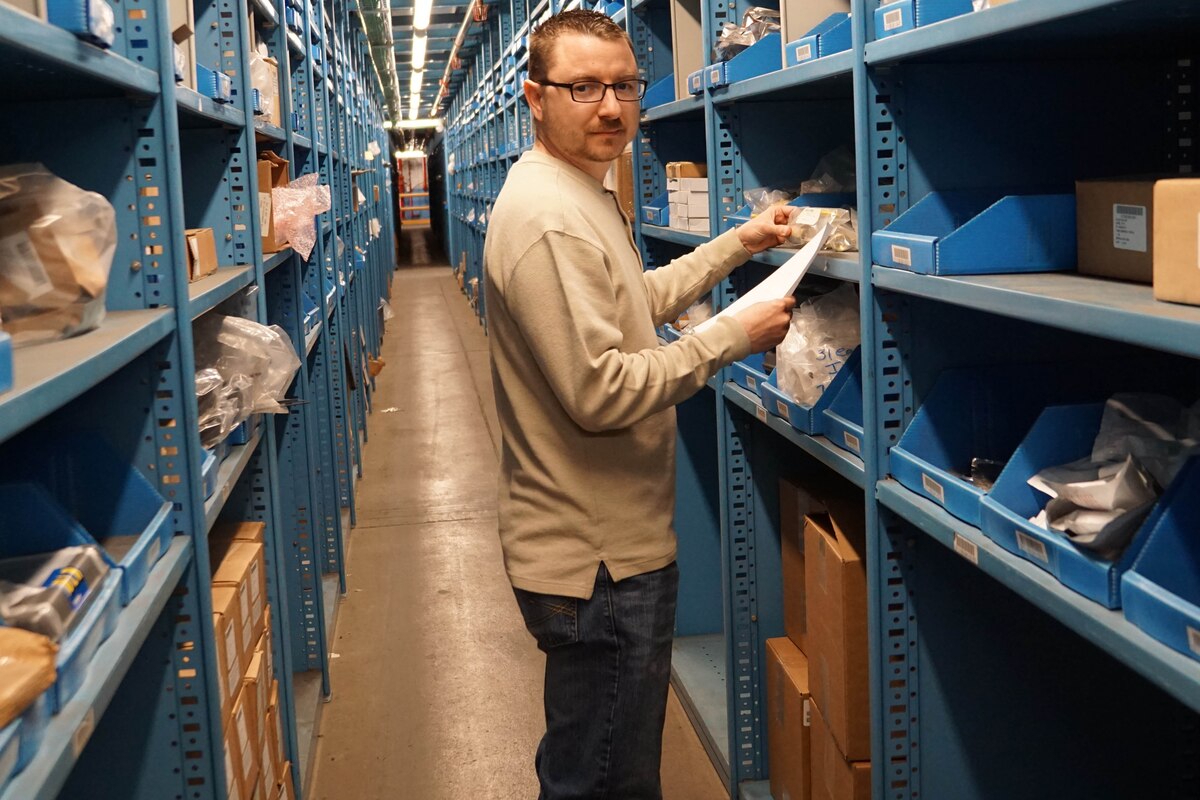 A man stands next to shelves in a warehouse.