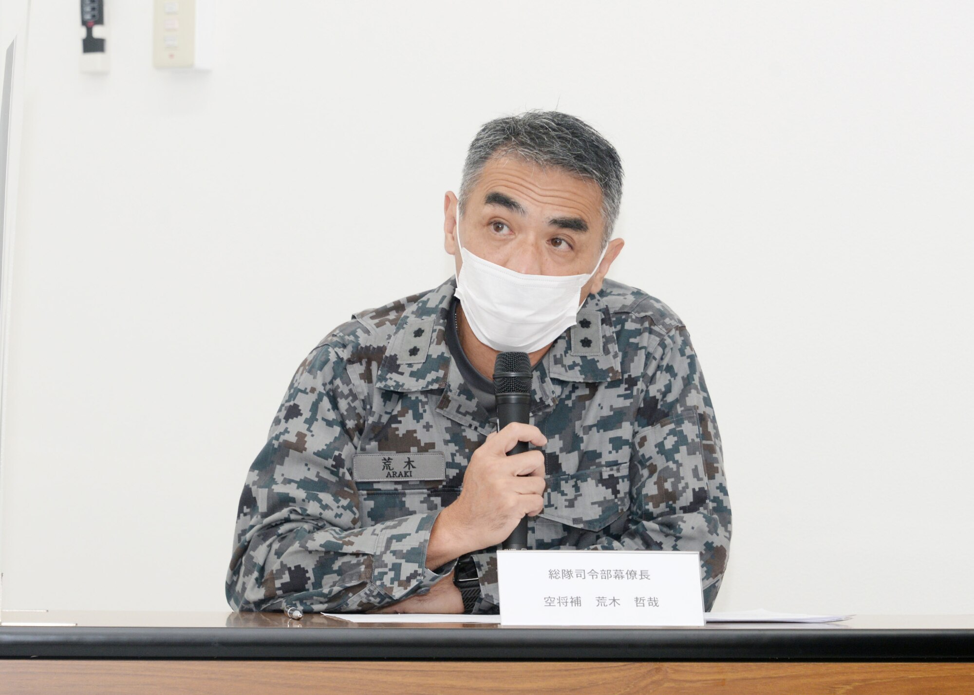 A man in uniform speaks into a microphone.