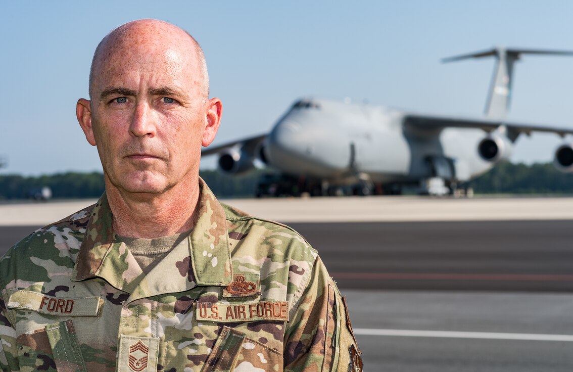 Chief Master Sgt. Bryan “Skip” Ford, 512th Aircraft Maintenance Squadron superintendent, poses for a photo near the flight line near a C-5M Super Galaxy on Dover Air Force Base, Delaware, Aug. 25, 2021. Ford recently recalled the events of Sept. 11, 2001, while stationed at Dover AFB and how 9/11 changed how he viewed our relative security and freedom as a nation. (U.S. Air Force photo by Roland Balik)