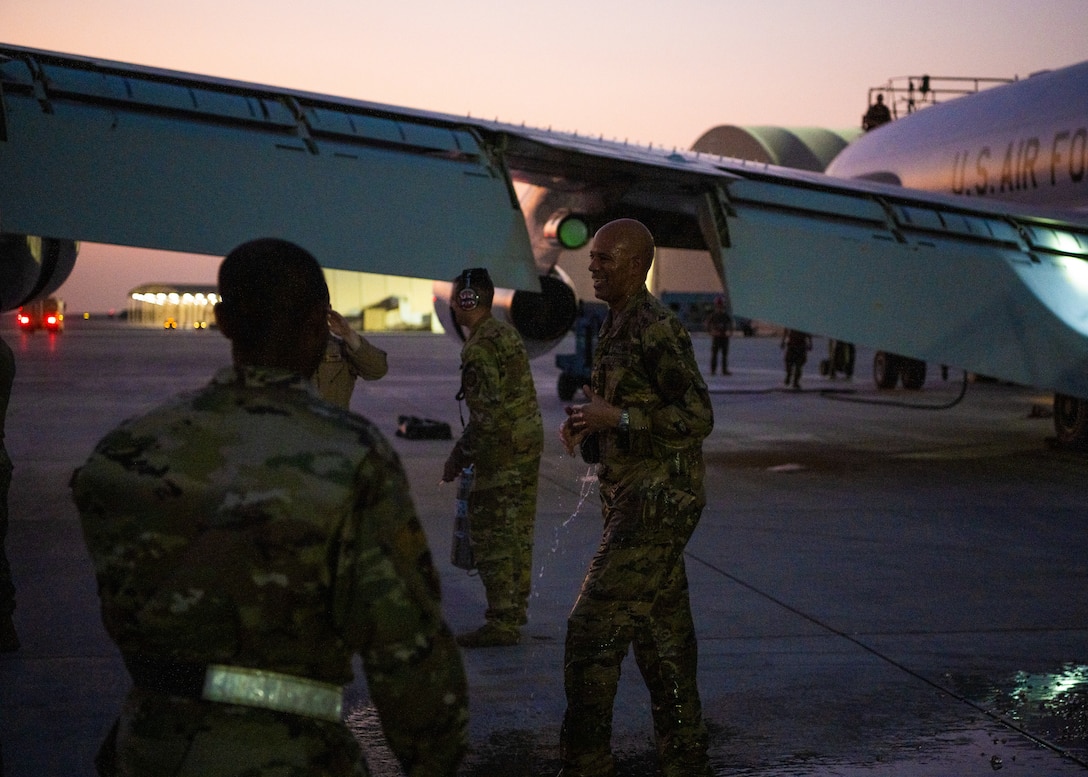 Airmen getting sprayed with water by several other Airmen as he exits an aircraft