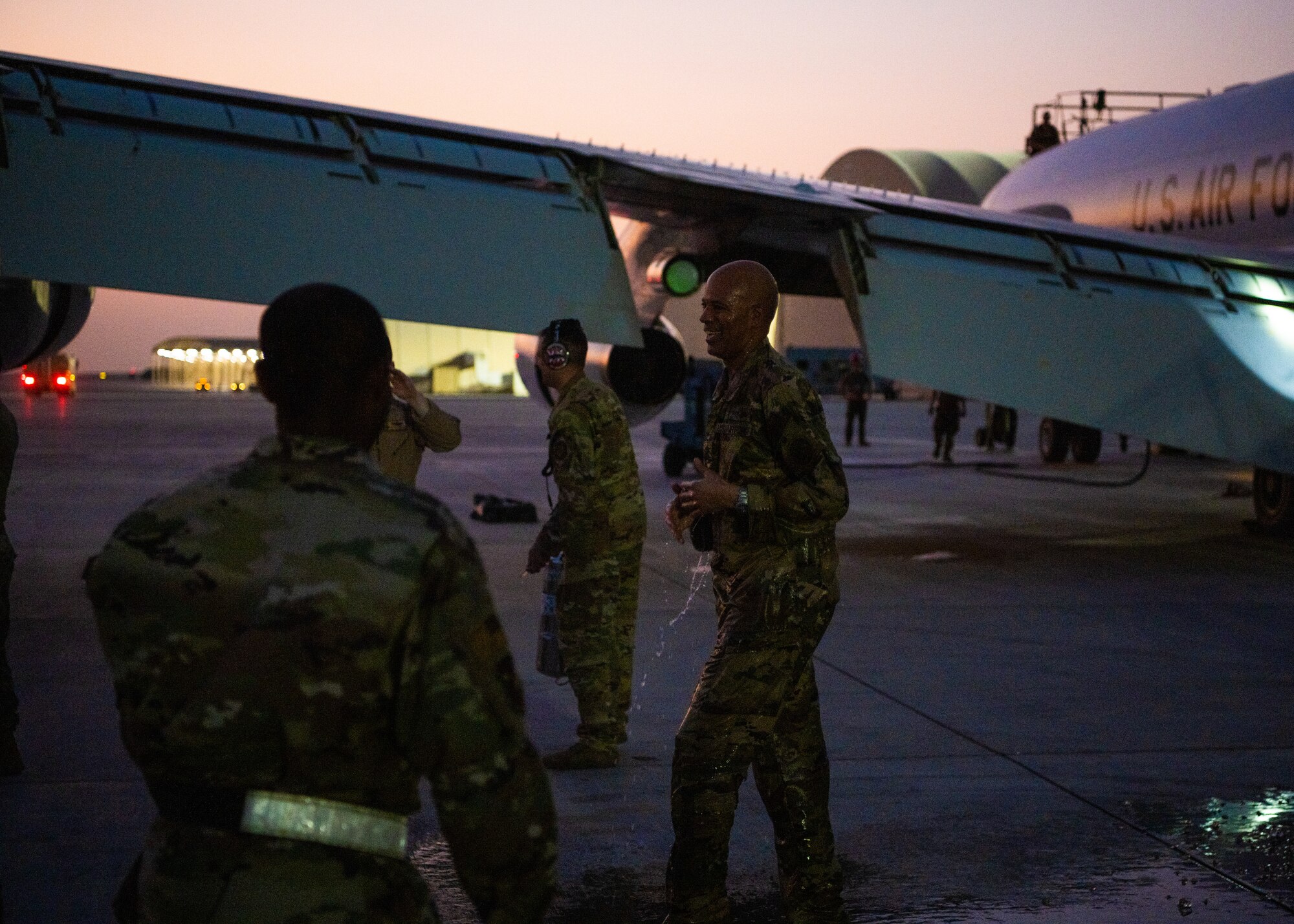 Airmen getting sprayed with water by several other Airmen as he exits an aircraft