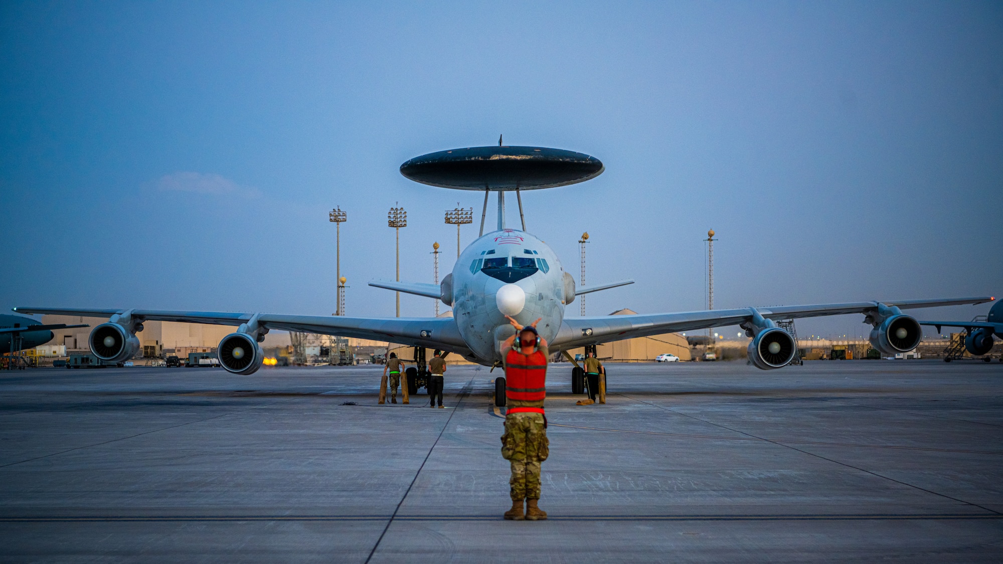 Airman signaling an E-3 Sentry aircraft into parking spot