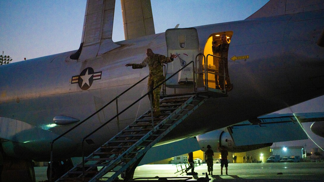 Airman gets sprayed with water by other Airmen as he exits an aircraft