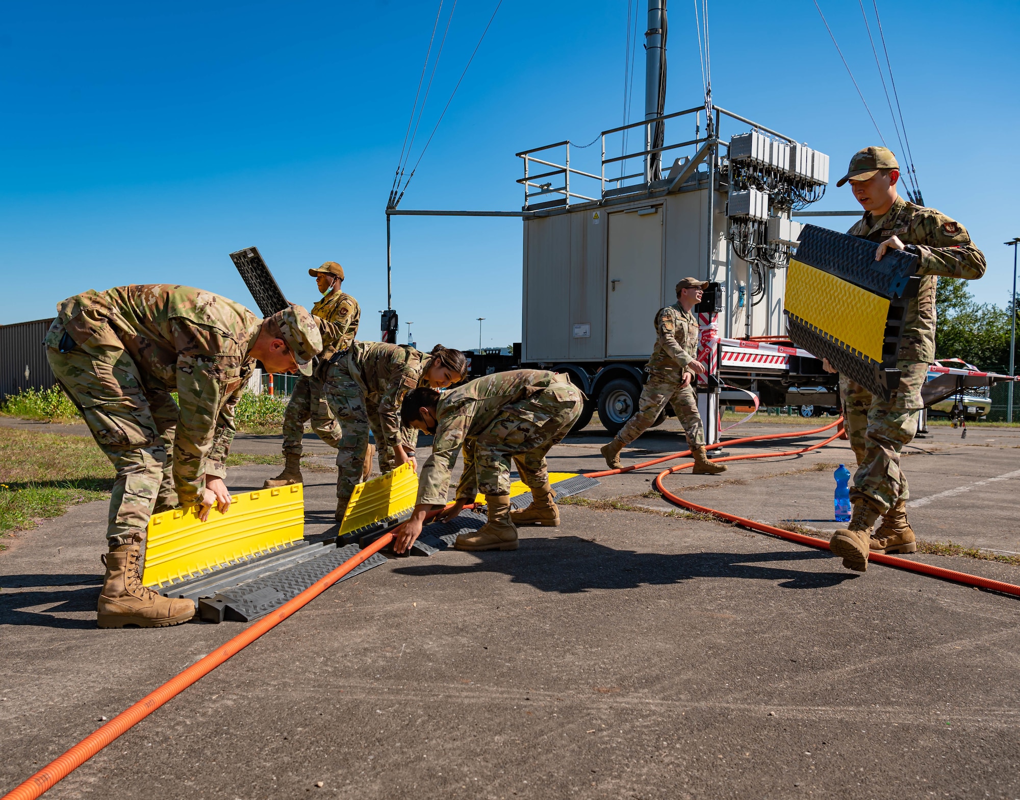 Airmen set-up safety mechanisms for mobile 5G tower.