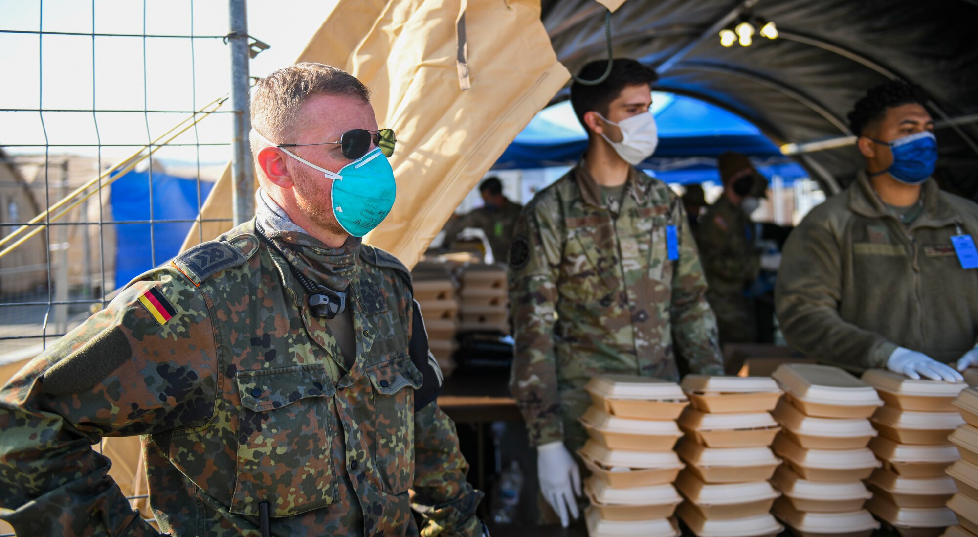 German military stands by food containers.