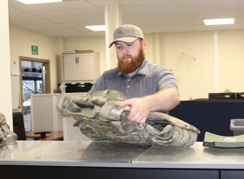 Dustin Wilson, the Central Issue Facility property book officer, at the 405th Army Field Support Brigade’s Logistics Readiness Center-Benelux, inspects an Improved Outer Tactical Vest, at the CIF facility at Chievres Air Base, Belgium. Wilson has been the property book officer for the main CIF at Chievres Air Base, Belgium, and the CIF annex in Brunssum, Netherlands, for almost two years.