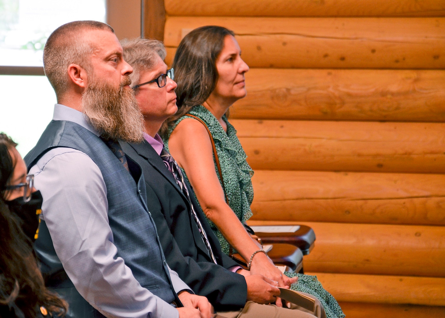 Profile of two men and a woman sitting listening to an unknown speaker