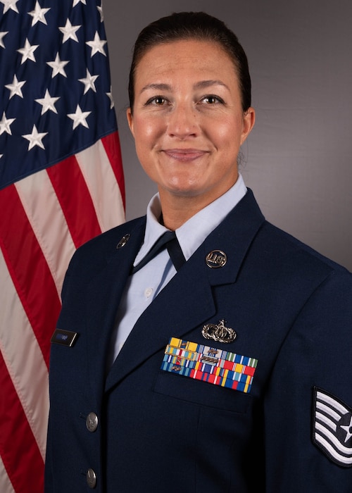 Official Photo of Tsgt Grace Huntoon, oboist and vocalist with the Concert Band and Full Spectrum, two of six ensembles at the Heritage of America Band, Langley Air Force Base, VA.  TSgt Huntoon is wearing blue service dress in front of the American flag.