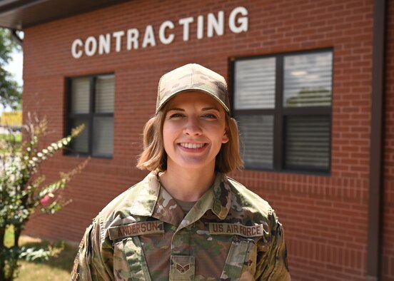 An Airman stands in front of a brick building.