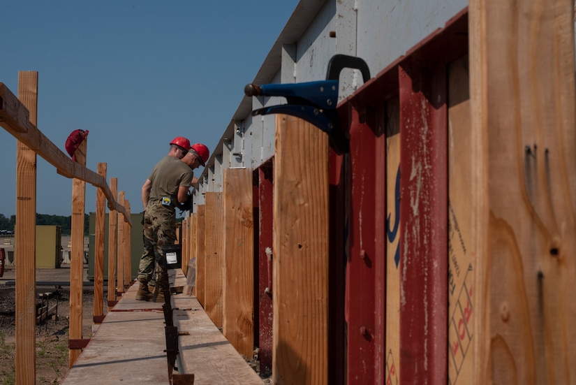 Members of the 201st Rapid Engineer Deployable Heavy Operational Repair Squadron Engineer (RED HORSE) Detachment 1 peer over a railing while constructing a KSPAN on Biddle Air National Guard Base in Horsham, Pennsylvania, July 27, 2021. The 201st RED HORSE provides the Department of Defense and the state of Pennsylvania with a self-sustaining engineer force capable of deploying to support both federal and domestic operations. (U.S. Air National Guard Photo by Senior Airman Wilfredo Acosta)