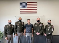 USAREC command teams pose for photo next to a blank wall.