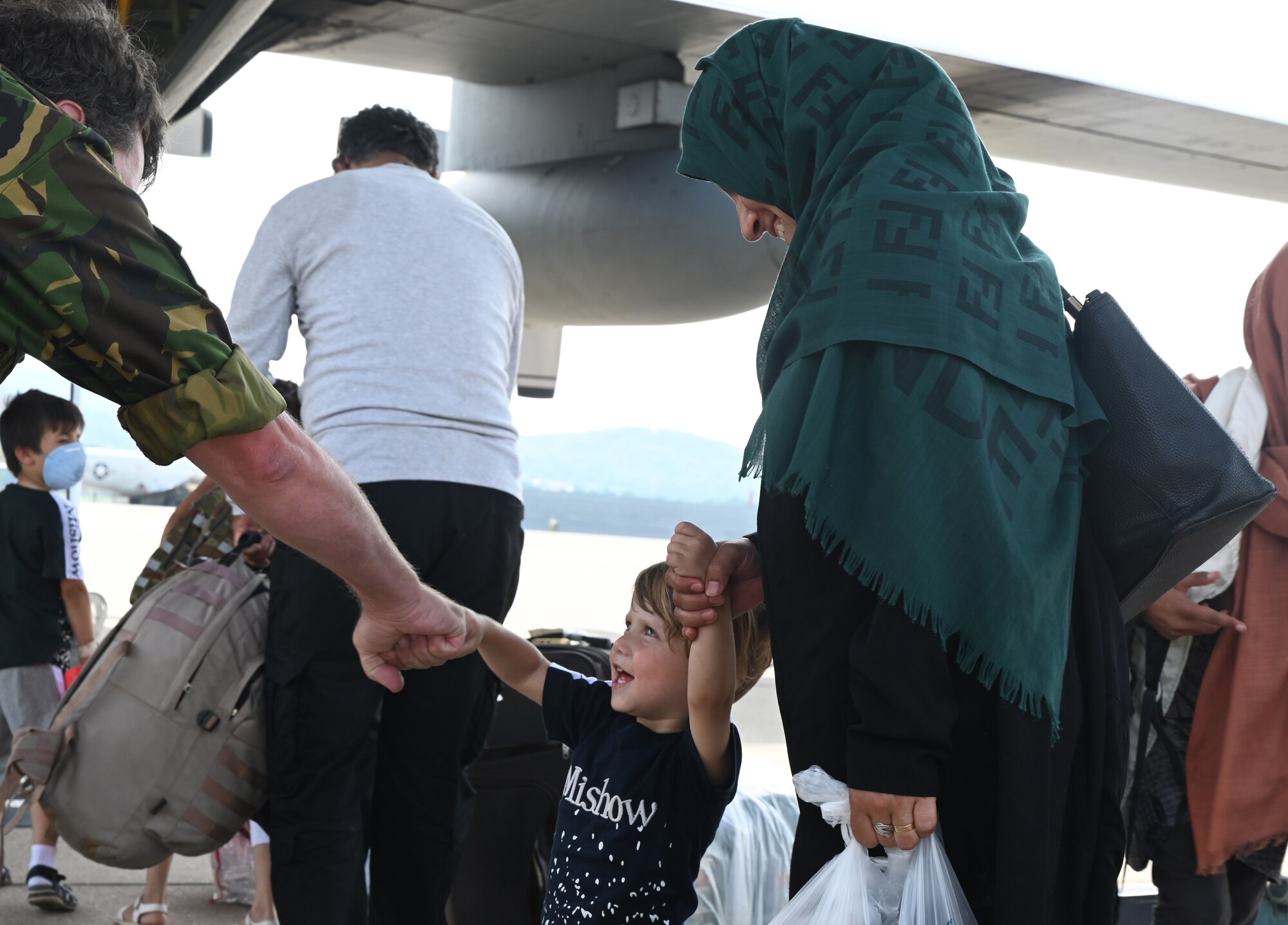 Royal Netherlands Air Force Lt. Col. Erik Berghuijs, fist bumps with a child at Ramstein Air Force Base, Germany, Sept. 7, 2021. Berghuijs and other NATO members helped ease evacuee concerns by loading their families on to a C-130 aircraft to be sent to an onward location. (U.S. Air Force photo by Senior Airman Thomas Karol)