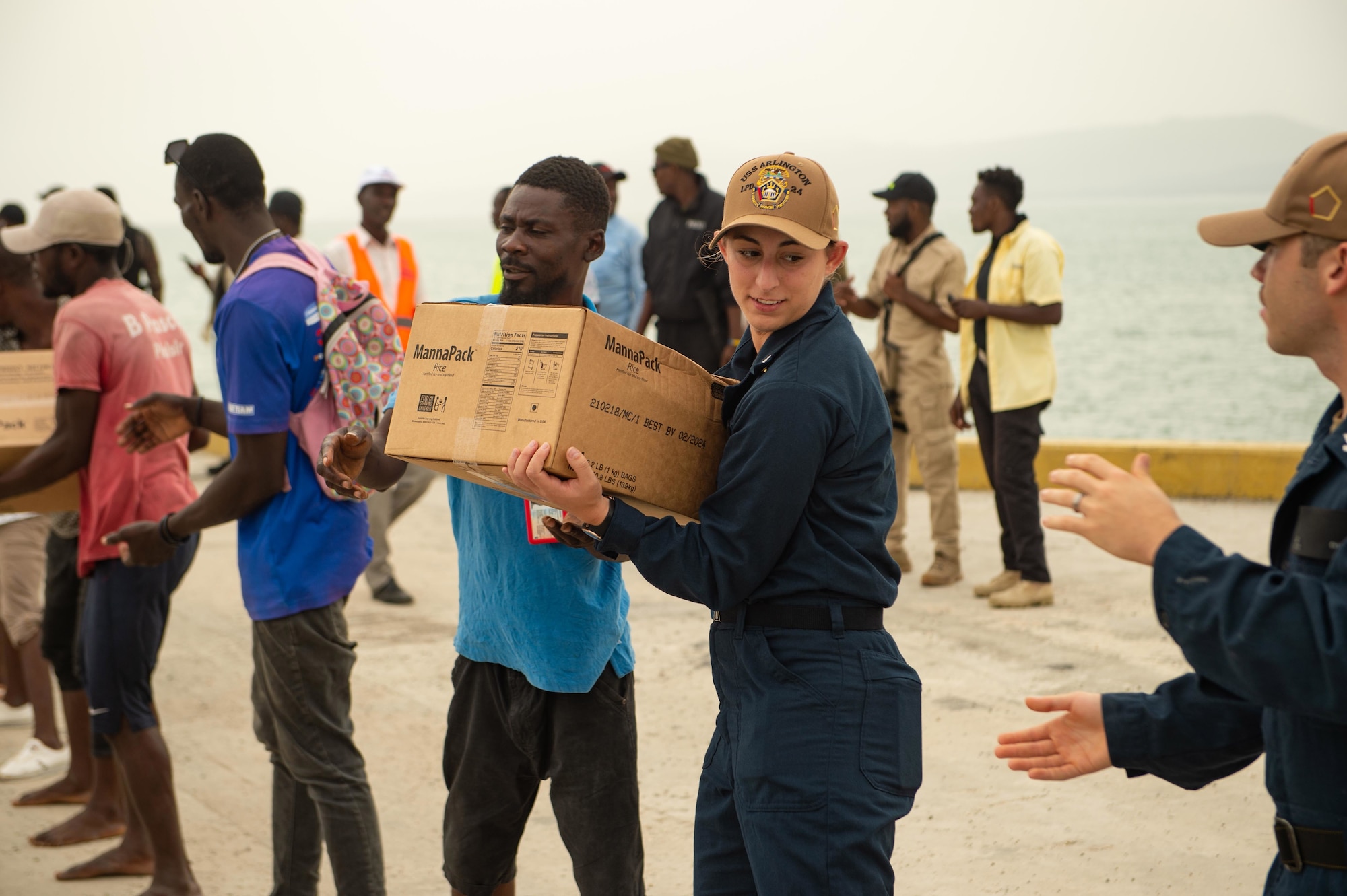 nformation System Technician 3rd Class Riley Hightower assigned to the San Antonio-class amphibious transport dock ship USS Arlington (LPD 24), works together with Haitians to load food into trucks at the Port of Jérémie, Haiti in support of a U.S. Agency for International Development (USAID) and Joint Task Force-Haiti humanitarian aid mission, Aug. 31, 2021. Arlington is deployed to U.S. Naval Forces Southern Command/U.S. 4th Fleet to support humanitarian assistance and disaster relief (HADR) efforts in Haiti following a 7.2-magnitude earthquake on Aug. 14, 2021.  (U.S. Navy photo by Mass Communication Specialist 2nd Class Jack D. Aistrup/Released)