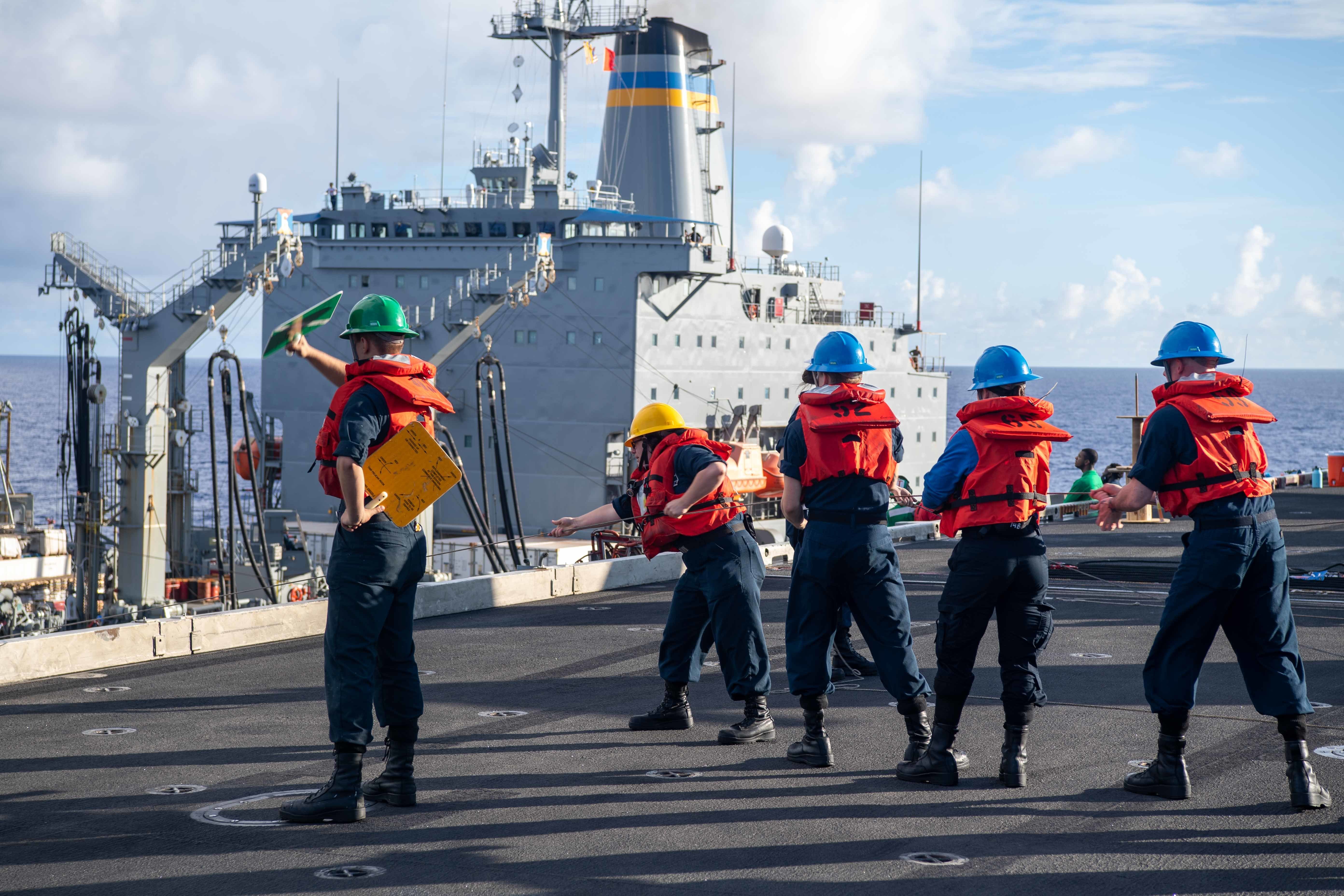 Sailors handle line on the flight deck aboard the aircraft carrier USS Carl Vinson (CVN 70) during a refueling-at-sea with Henry J. Kaiser-class fleet replenishment oiler USNS Yukon (T-AO 202), Sept. 3.