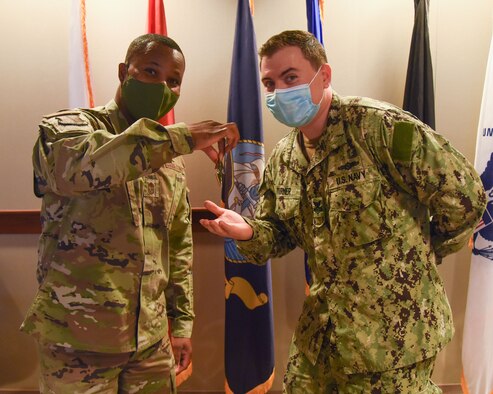 U.S. Air Force Chief Master Sgt. Marcus Washington, 17th Medical Group superintendent, presents a coin to Petty Officer 1st Class Tyler Turner, Center for Information Warfare Training Detachment instructor for his outstanding performance in his field at CIWT on Goodfellow Air Force Base, Texas, Sept. 7, 2021. Turner was recognized for his leadership and guidance of his 250 average yearly students. (U.S. Air Force photo by Staff Sgt. Tyrell Hall)