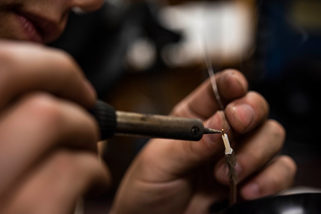 An Airmen solders wires.