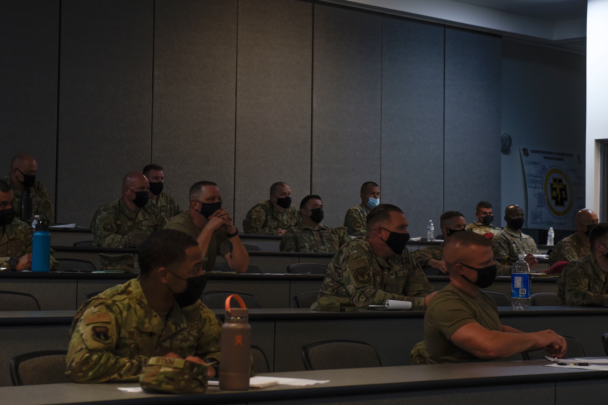 A classroom filled with people sitting at desks.