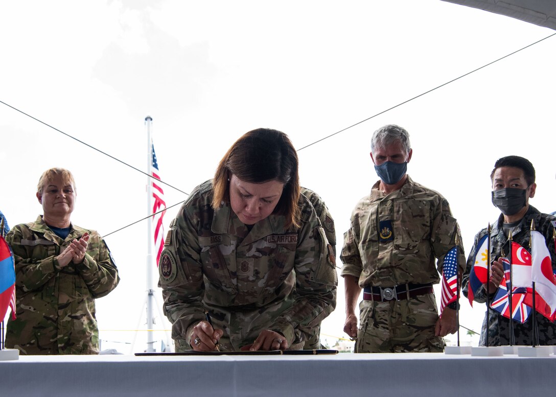 Chief Master Sgt. of the Air Force JoAnne S. Bass signs a charter document agreeing upon and signed by senior enlisted leaders from across the Indo-Pacific region at the battleship USS Missouri, Ford Island, Hawaii, during a Senior Enlisted Leadership Summit, Sep. 1, 2021. The charter laid out goals to strengthen relationships and focus on prosperity and security for all.