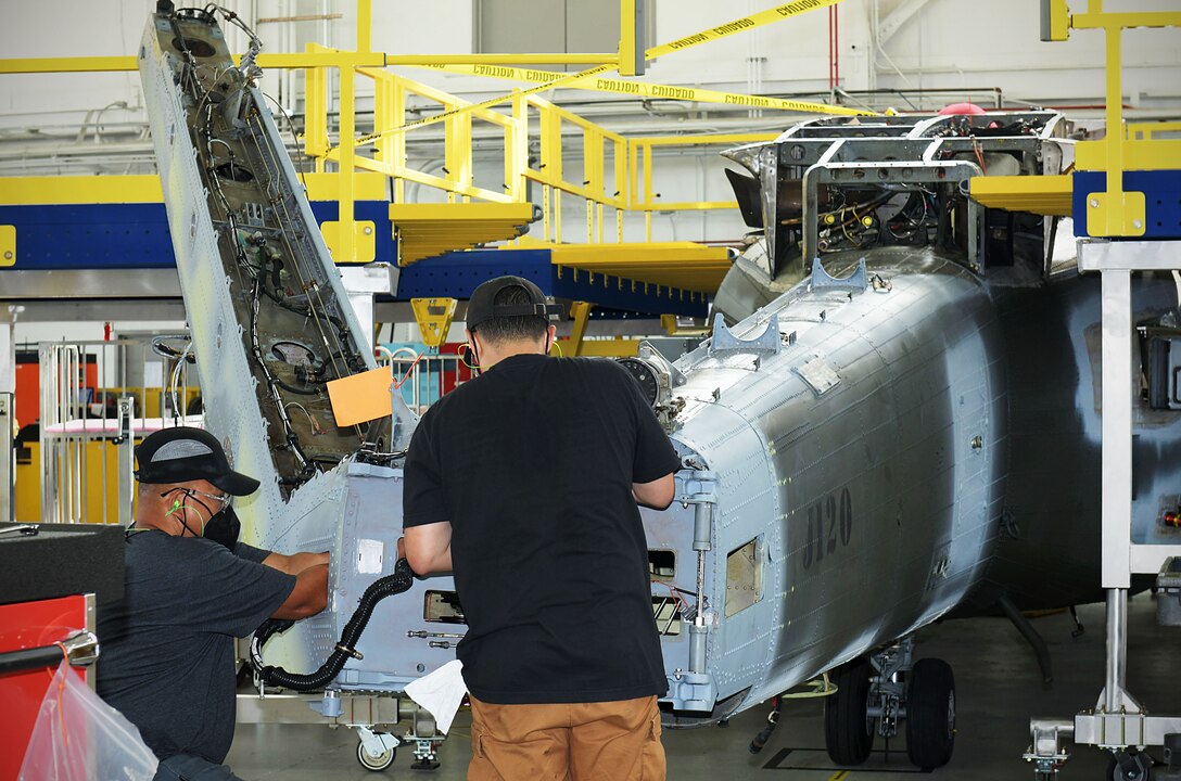 Aircraft mechanic Mario Orejudos and aircraft mechanic apprentice Obeiean Pagaduan install tail pylon swivel fittings on an H-60 aircraft.