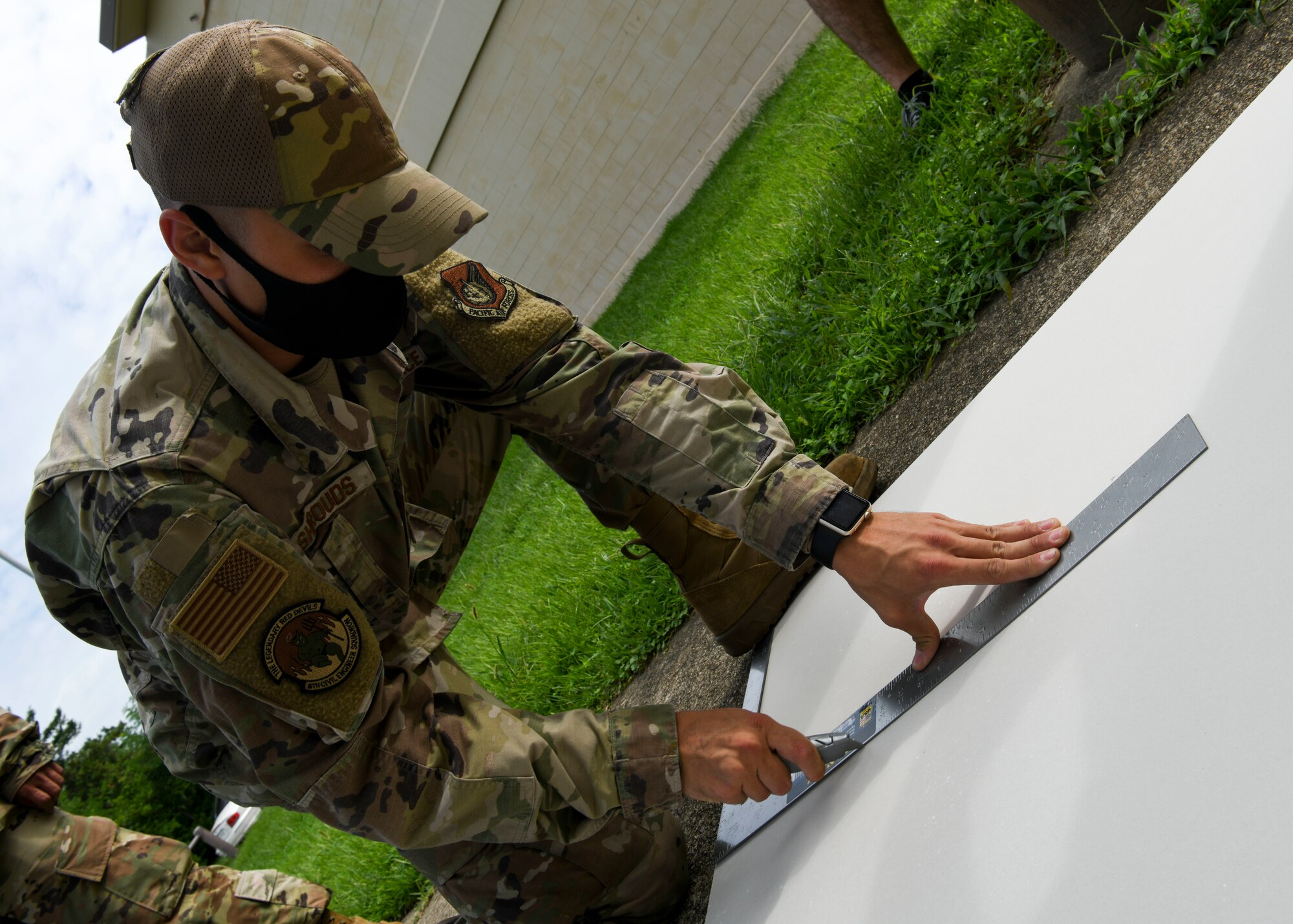 An Airman cuts a sheet of paper.
