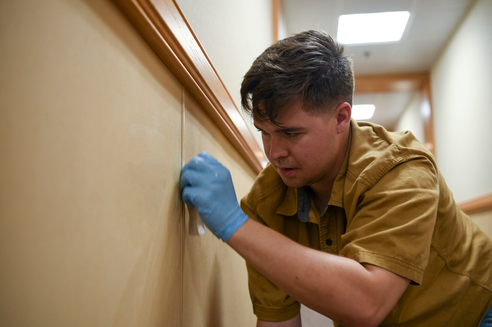 An Airman cleans a wall.