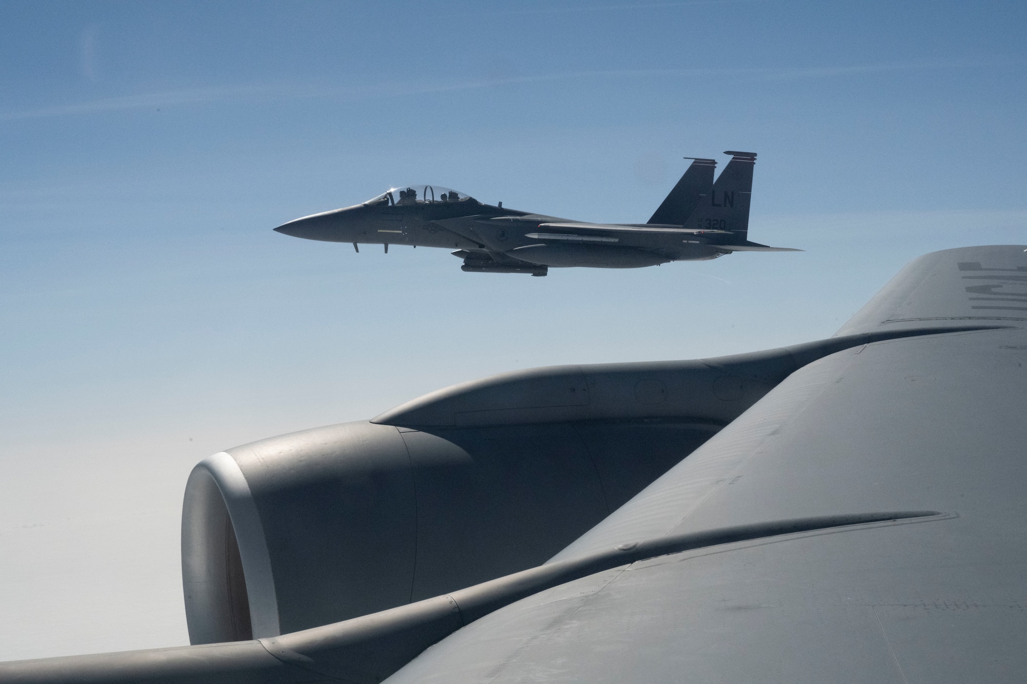 A U.S. Air Force F-15E Strike Eagle assigned to the 48th Fighter Wing flies alongside a KC-135 Stratotanker assigned to the 100th Air Refueling Wing at Royal Air Force, Mildenhall, England, Sept. 1, 2021. The 100th ARW is the only permanent U.S. air refueling wing in the European theater providing the critical air refueling "bridge" that allows the Expeditionary Air Force to deploy around the globe on a moment's notice. (U.S. Air Force photo by Airman Alvaro Villagomez)