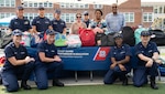 Chaplain Andrew Hoyle (standing, back left), Coast Guard headquarters’ Partnership in Education (PIE) coordinator, along with Coast Guard and Department of Homeland Security (DHS) volunteers, pose in front of a table full of backpacks stuffed with school supplies at Anita J. Turner Elementary School during a back-to-school night event, August 26th. Hundreds of Coast Guard and DHS volunteers donated equipment or helped pack backpacks with schools supplies to support the D.C. community through St. Elizabeth’s Back-to-School backpack and supply drive (Coast Guard photo by Patrick Ferraris).