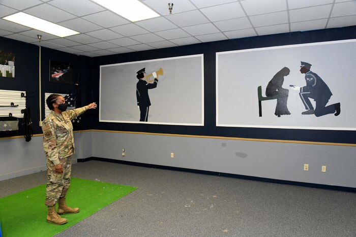 Photo shows woman pointing at two large paintings of the honor guard on the wall.