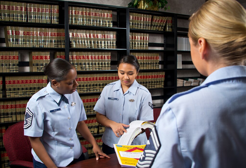 Paralegals in law library reviewing legal manual.